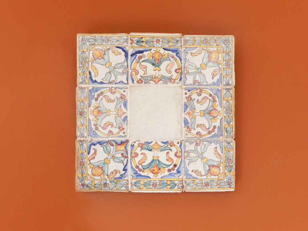 square blue and multicolored wall decor on orange wall