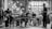 A black and white photograph captures a group of five musicians performing. The setup includes a bass player, a keyboardist, a drummer, and a saxophonist, all engaging in a lively and collaborative music session. The background features shelves stocked with wine bottles and soft ambient lighting adds to the intimate atmosphere.