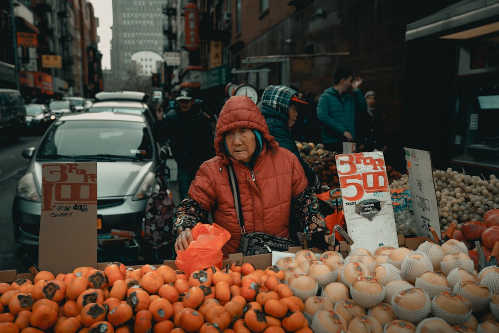 Mujer vendiendo frutas cerca del vehículo estacionado en la calle durante el día