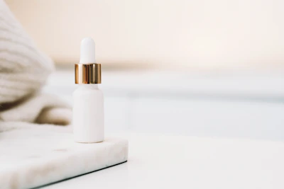 Elegant dropper bottle of brightening serum resting on a marble surface with fresh flowers