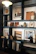A stylish and modern shelving unit displays an assortment of framed abstract artworks, decorative vases, and neatly stacked books. The shelves are filled with a warm palette of beige, brown, and black tones, providing a sophisticated and artistic ambiance.
