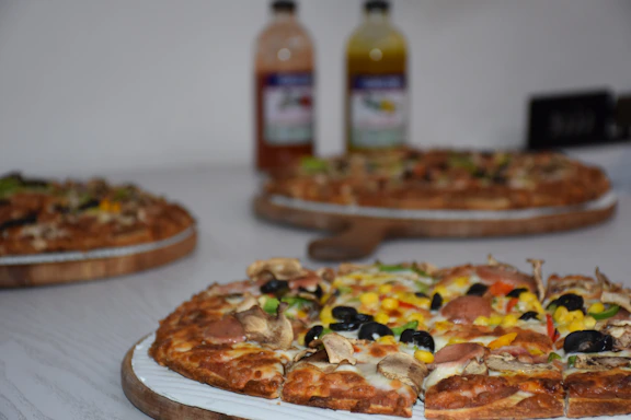 A colorful overhead shot of six different pizzas arranged on a rustic wooden table, each topped with fresh ingredients and vibrant colors.