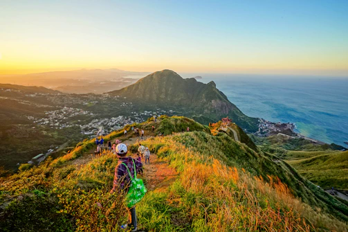 A scenic view from a Knot & Compass Travel trip showing a group hiking along a rugged coastline at sunrise.