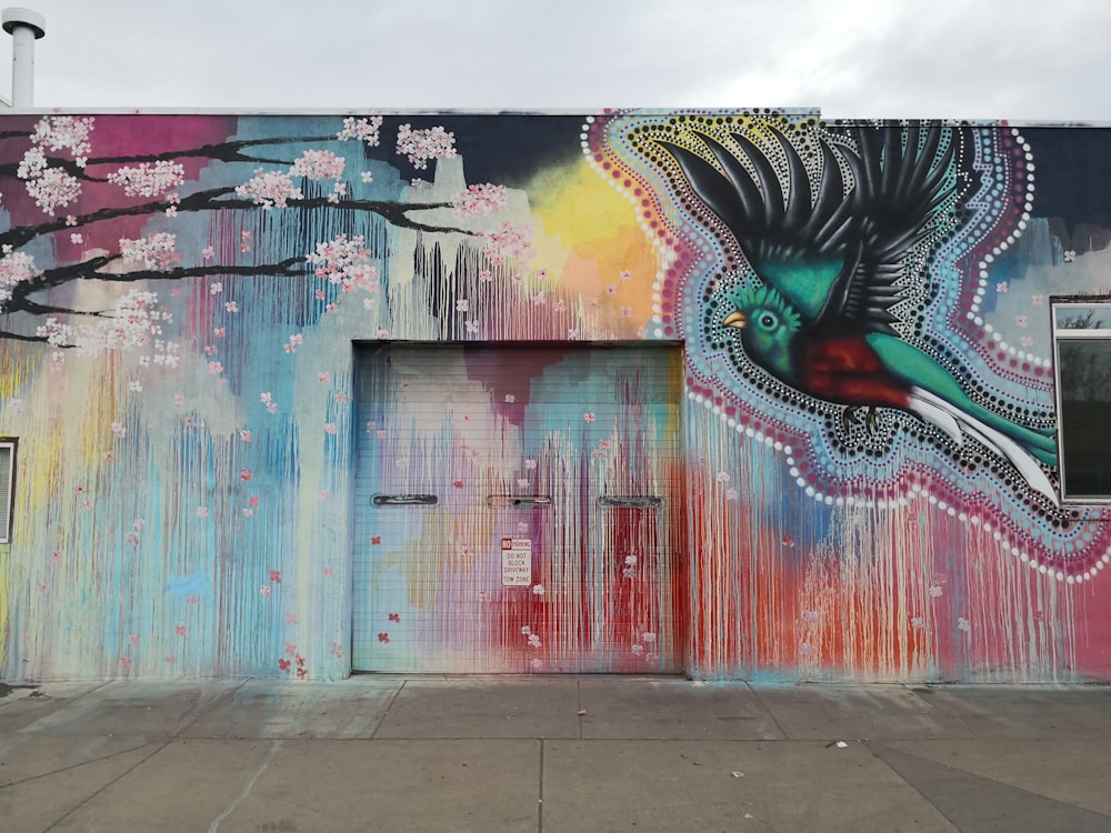 green and red bird flying over pink cherry blossom print building