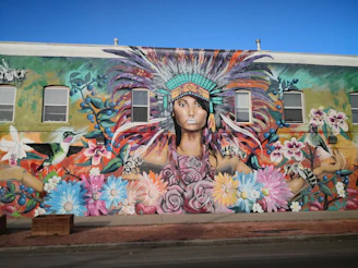 Artists painting murals inspired by axolotl motifs surrounded by native flora.