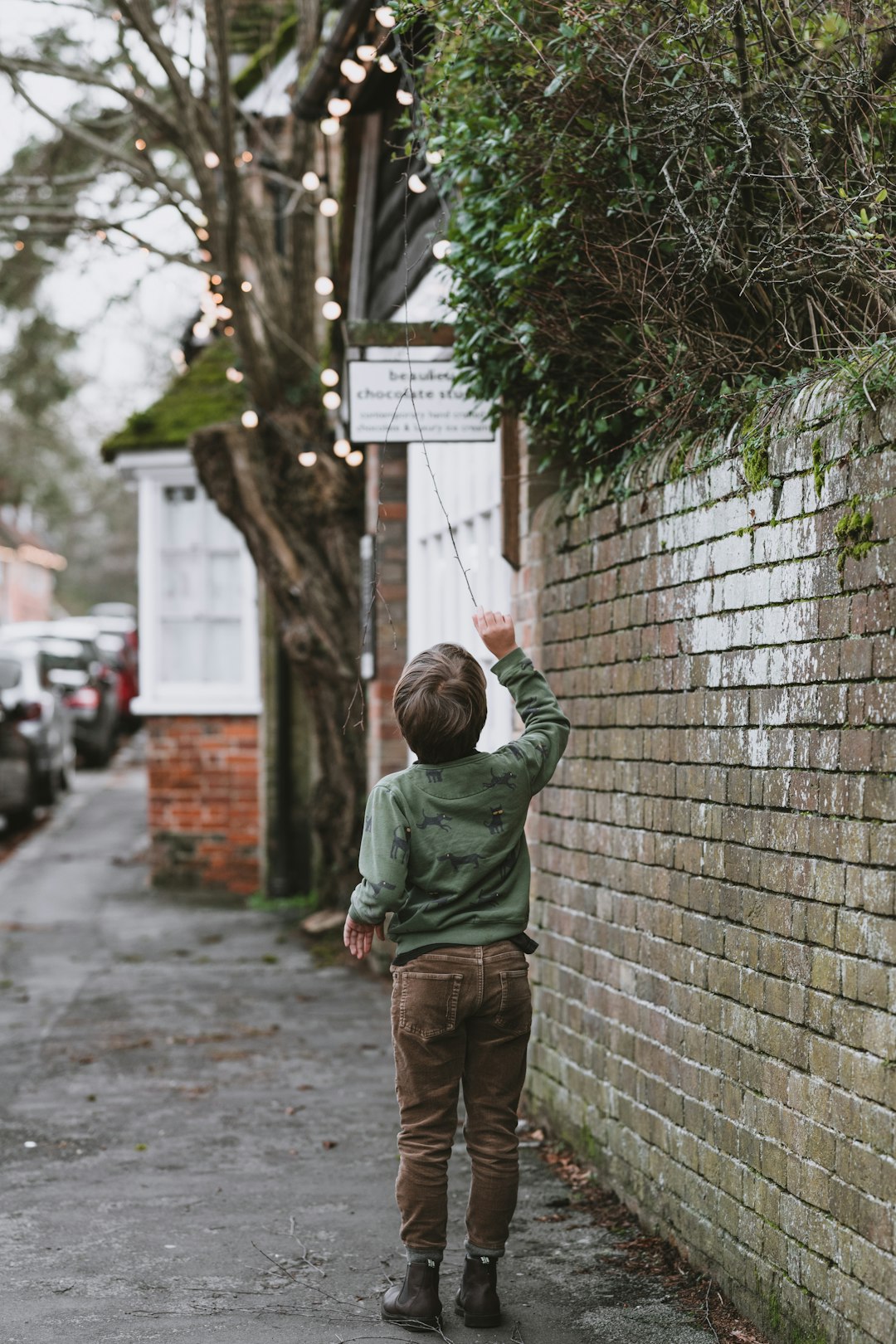 boy walking beside wall during daytime