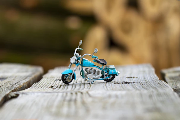 Motorcycle battery resting on a rustic wooden surface with a blurred road in the background.