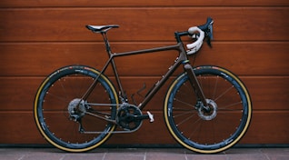 black road bike against wooden wall