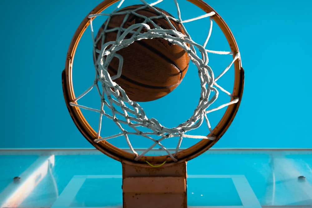 pallacanestro marrone vicino all'anello di pallacanestro