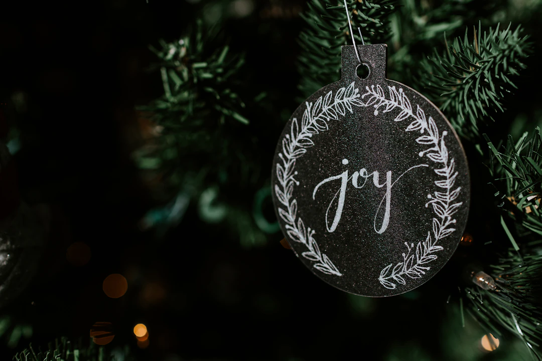 Fekete karácsonyfadísz „joy” felirattal a fán