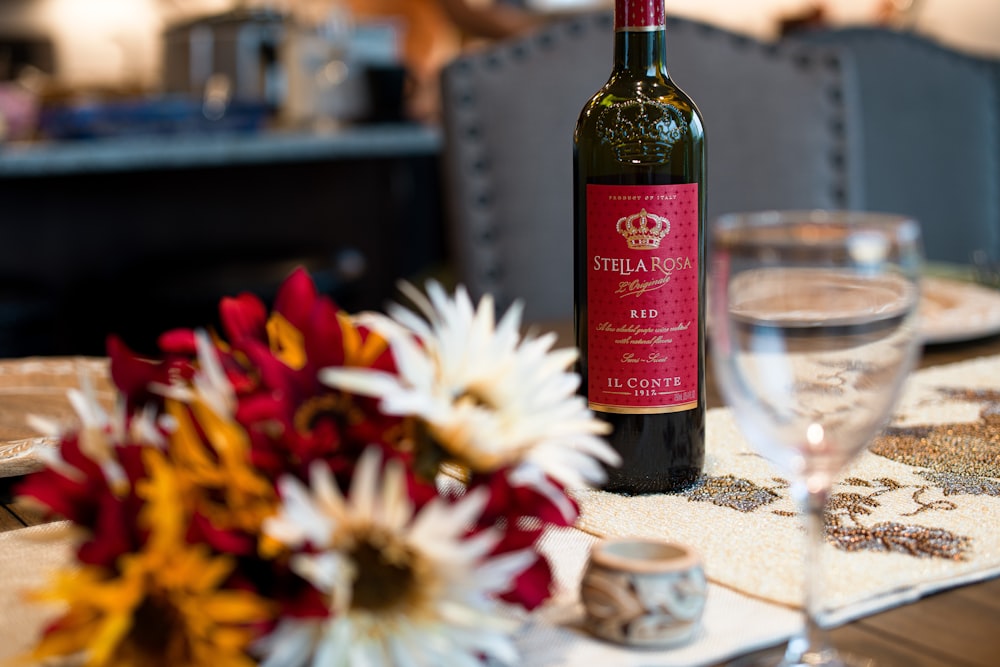 flowers beside wineglass near wine bottle