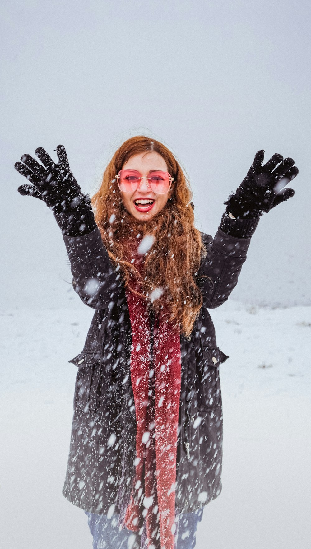 mujer sonriendo y levantando las manos en un campo de nieve
