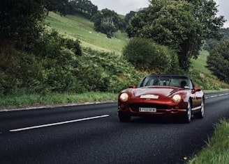 A convertible with the top down on a sunny countryside highway