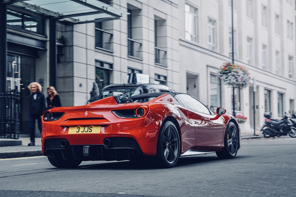 red sports coupe on road near people and building