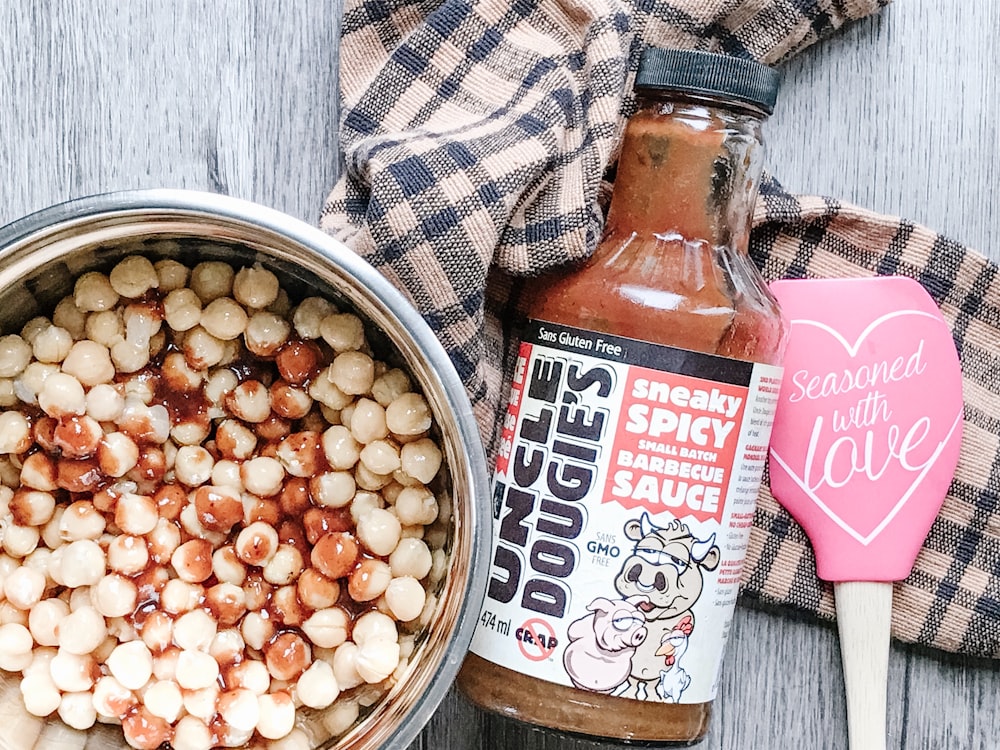 ball like food on gray stainless steel bowl beside Uncle Dougie's sneaky spicy sauce bottle