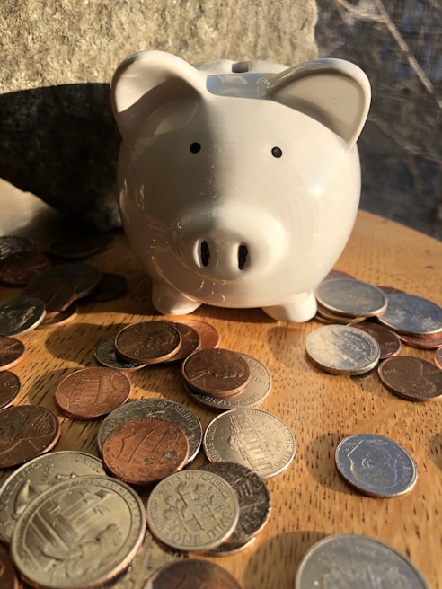 Close-up of hands holding Colombian pesos and a small piggy bank on a wooden table.