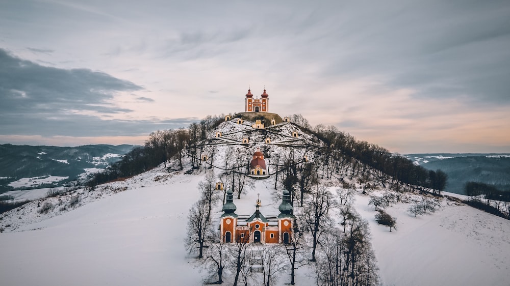 brown and gray church on snowy field viewing mountain under white and gray sky