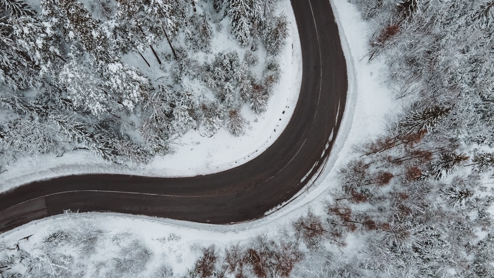 aerial photography of gray spiral road near field and trees covered with snow