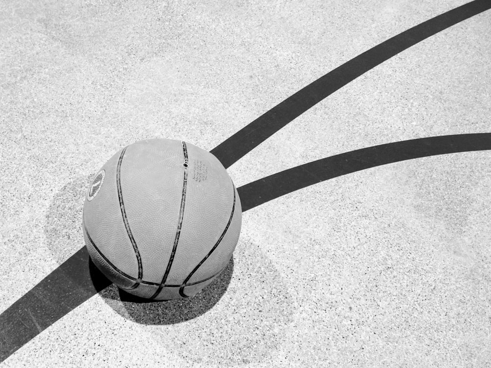 Fotografía en escala de grises de baloncesto sobre pavimento de hormigón
