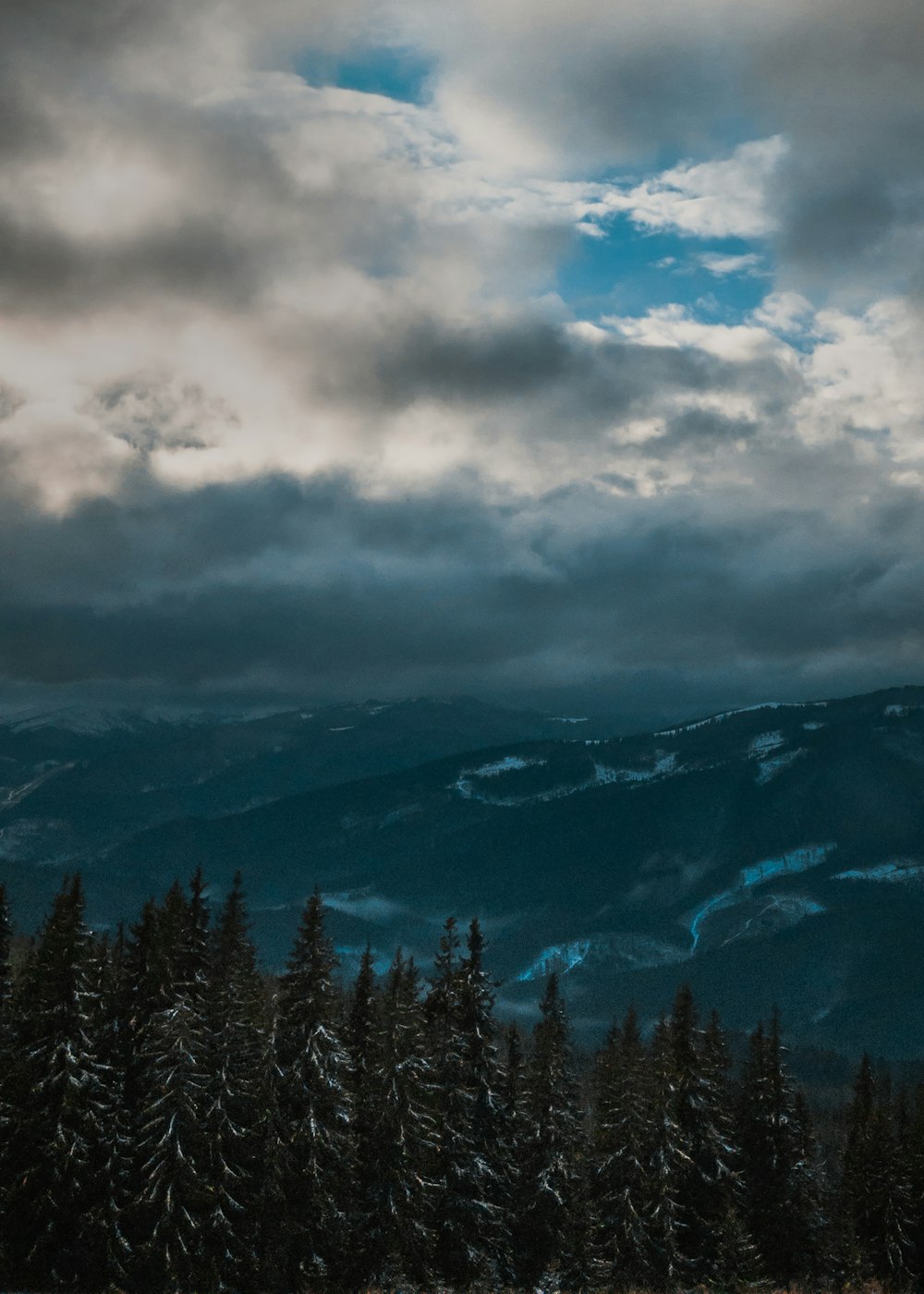 a view of a mountain range with trees in the foreground