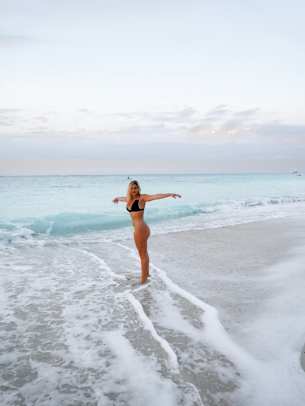 woman in black bikini top standing beside seashore during daytime