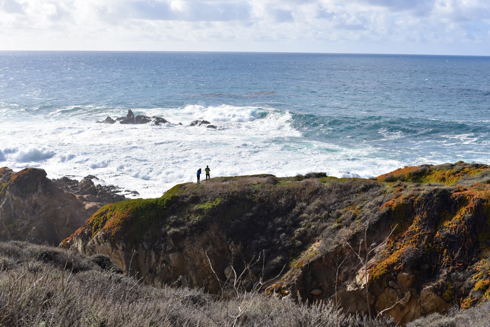 two person standing on cliff
