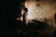 A shadowy figure walking through a foggy forest lit by subtle neon lights.