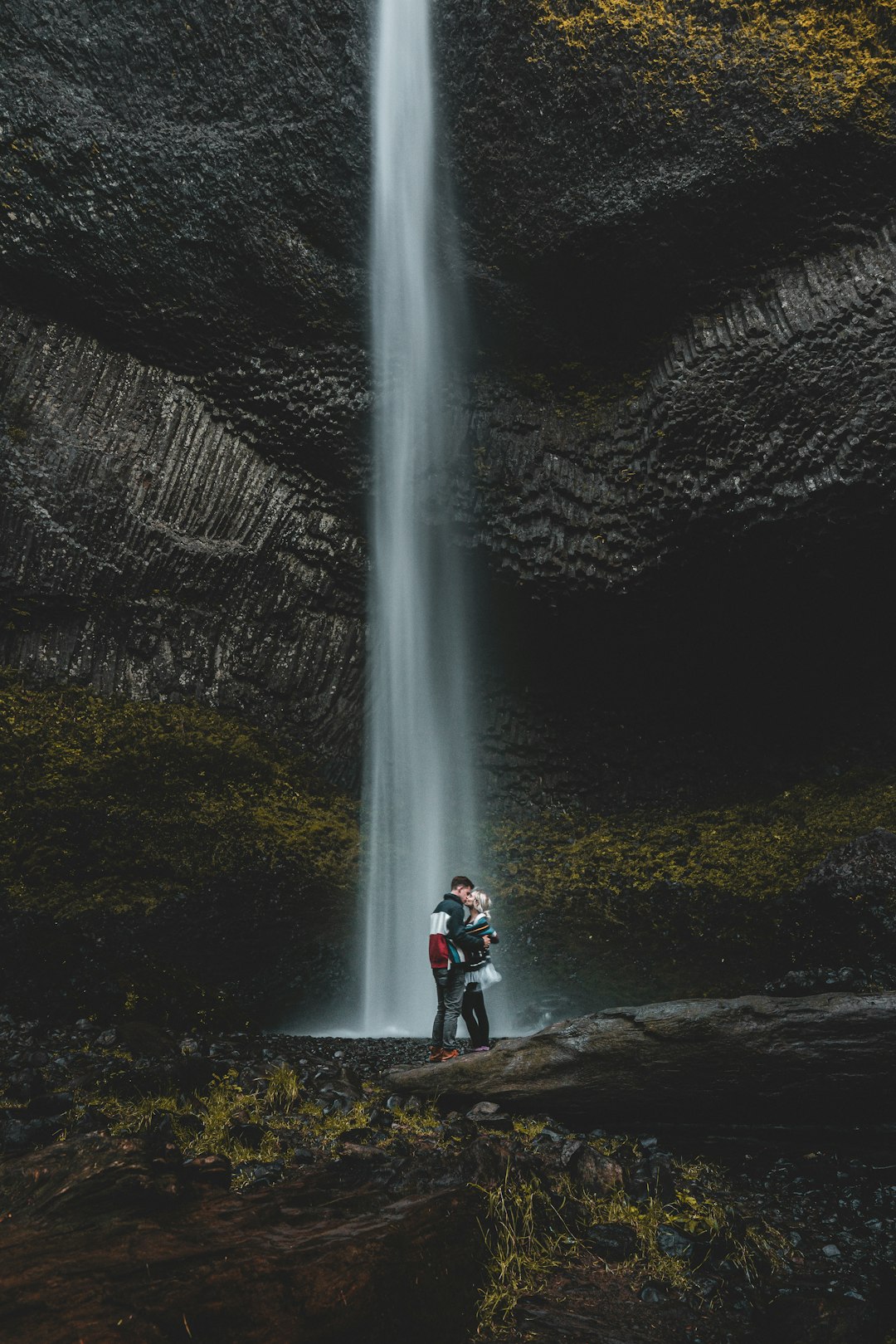 man and woman kissing near waterfalls