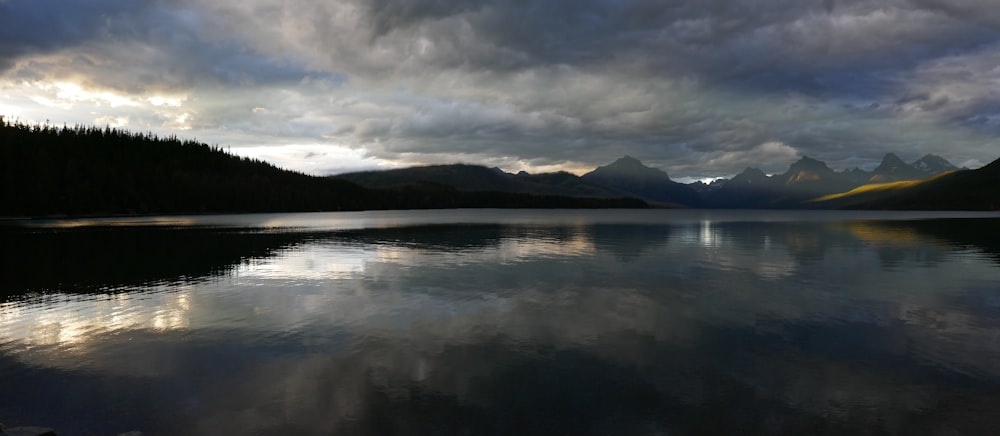 mountains near body of water under cloudy sky