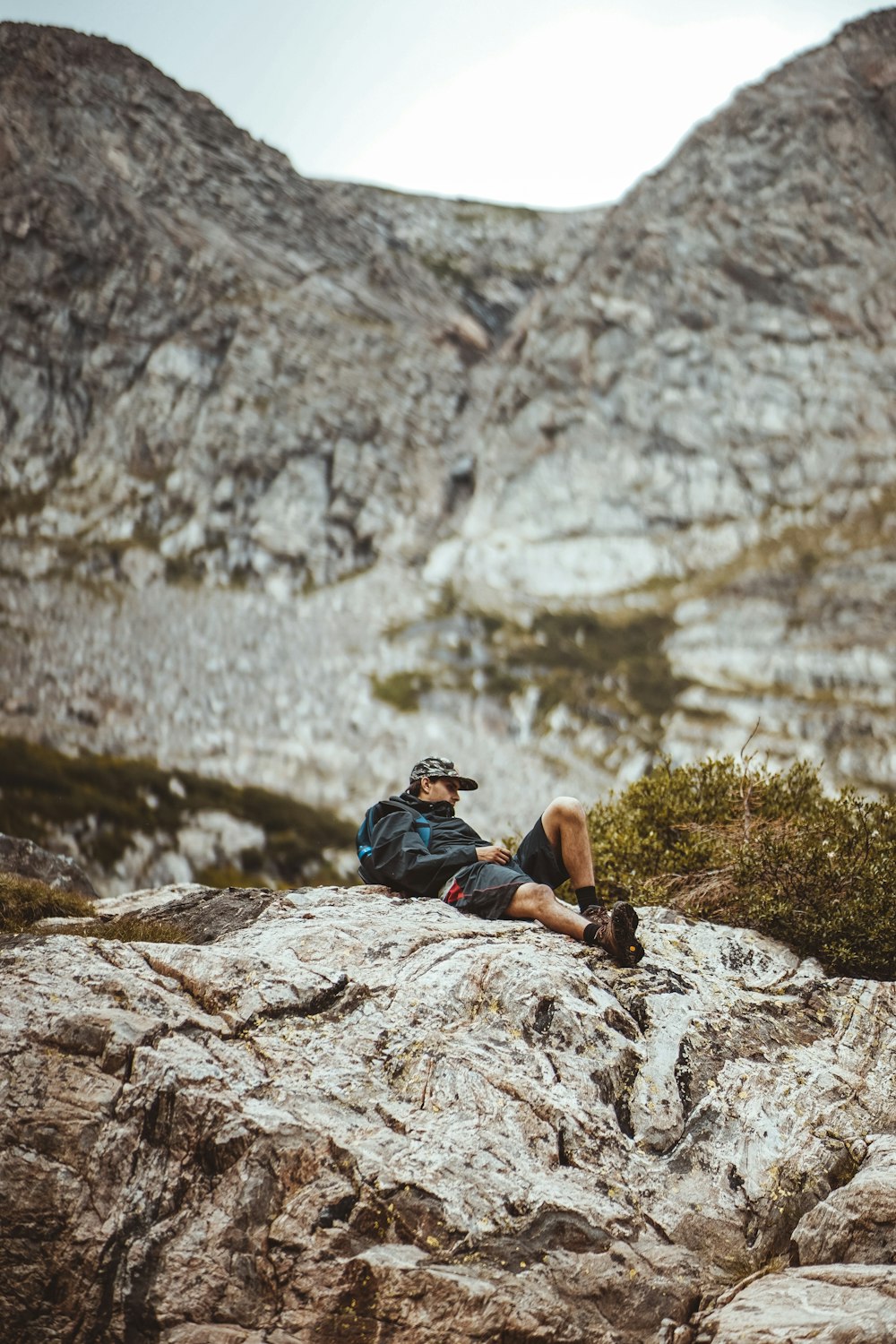 man lying down on gray rock