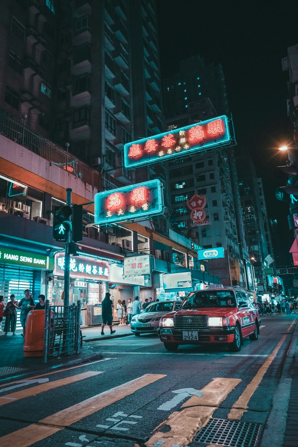 people walking on pathway near buildings and different vehicles on road during night time