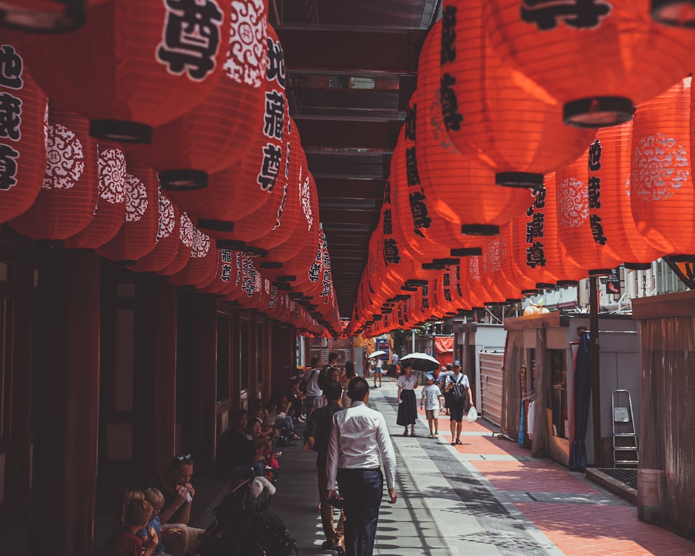 people walking and sitting under red Chinese lanterns