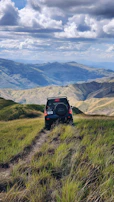 Robust black SUV navigating a rugged mountain trail under a clear blue sky.