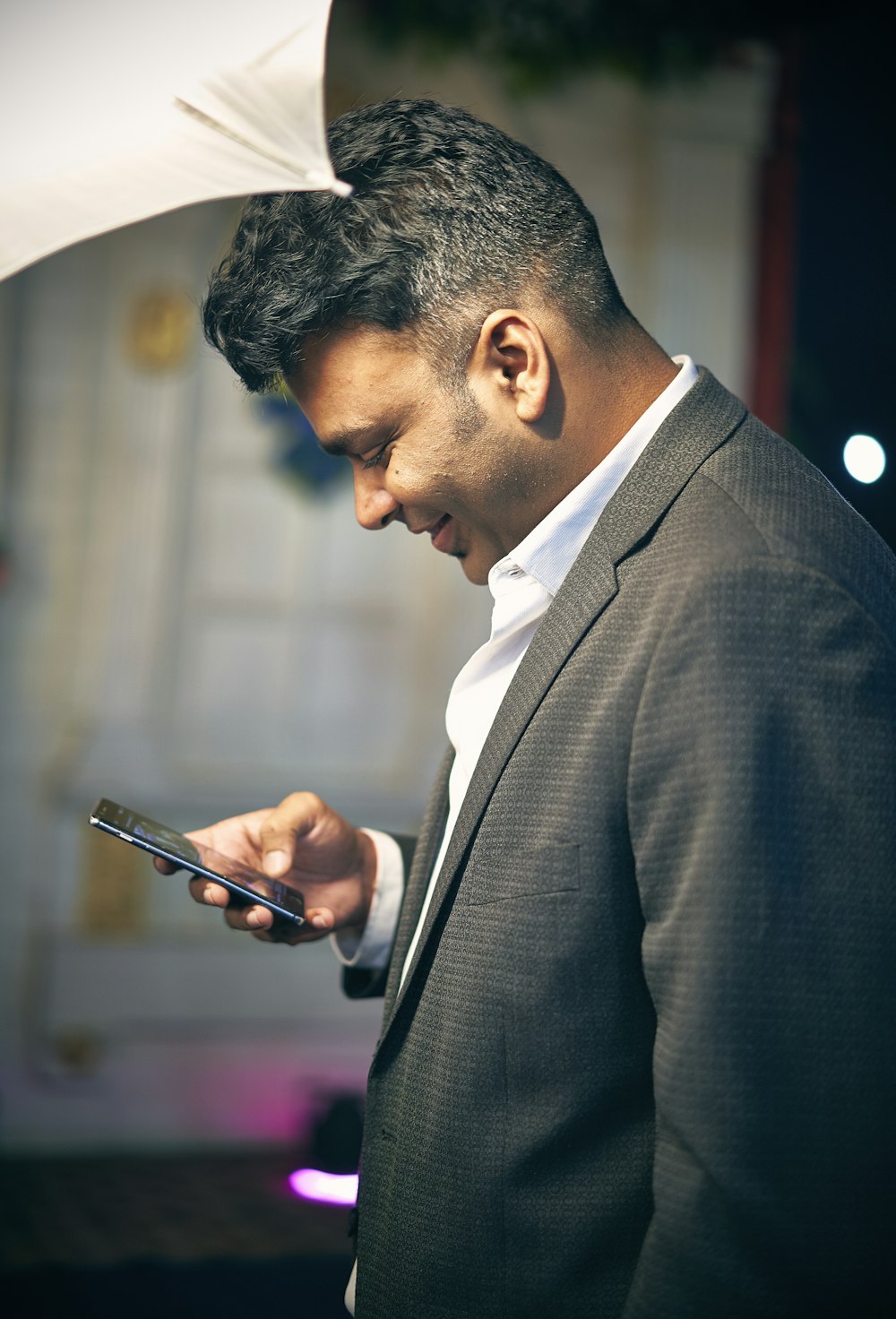 man standing near wall while holding smartphone