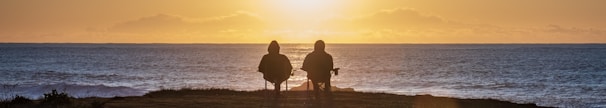 two people sitting on seashore