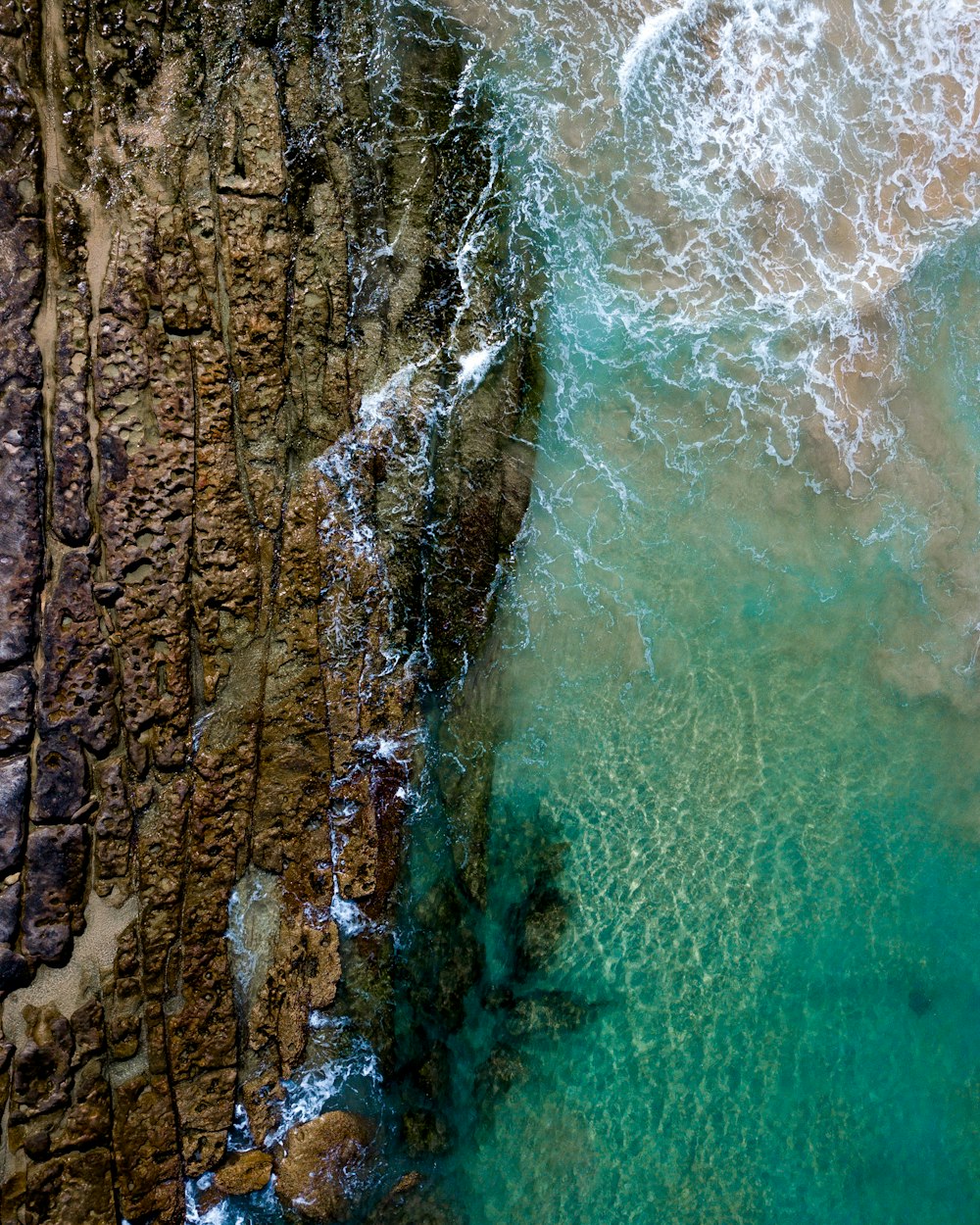 an aerial view of the ocean and rocks