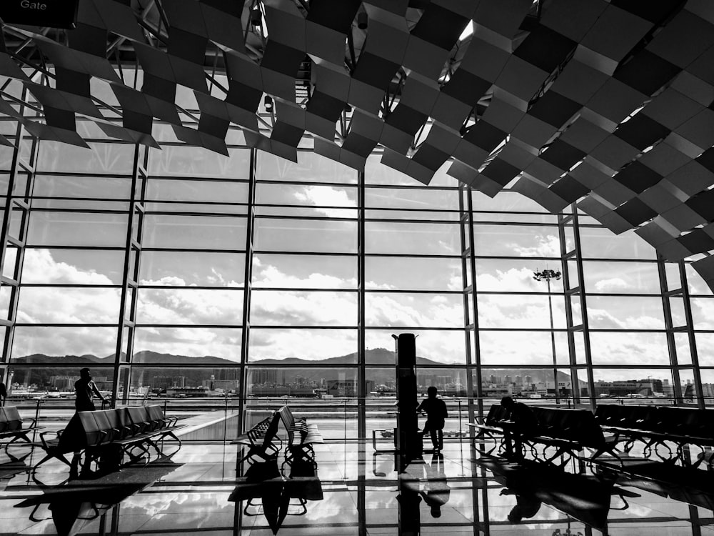 grayscale photography of few people inside the airport