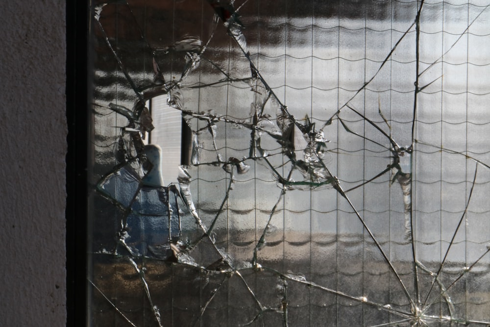 a broken window with a blue fire hydrant behind it