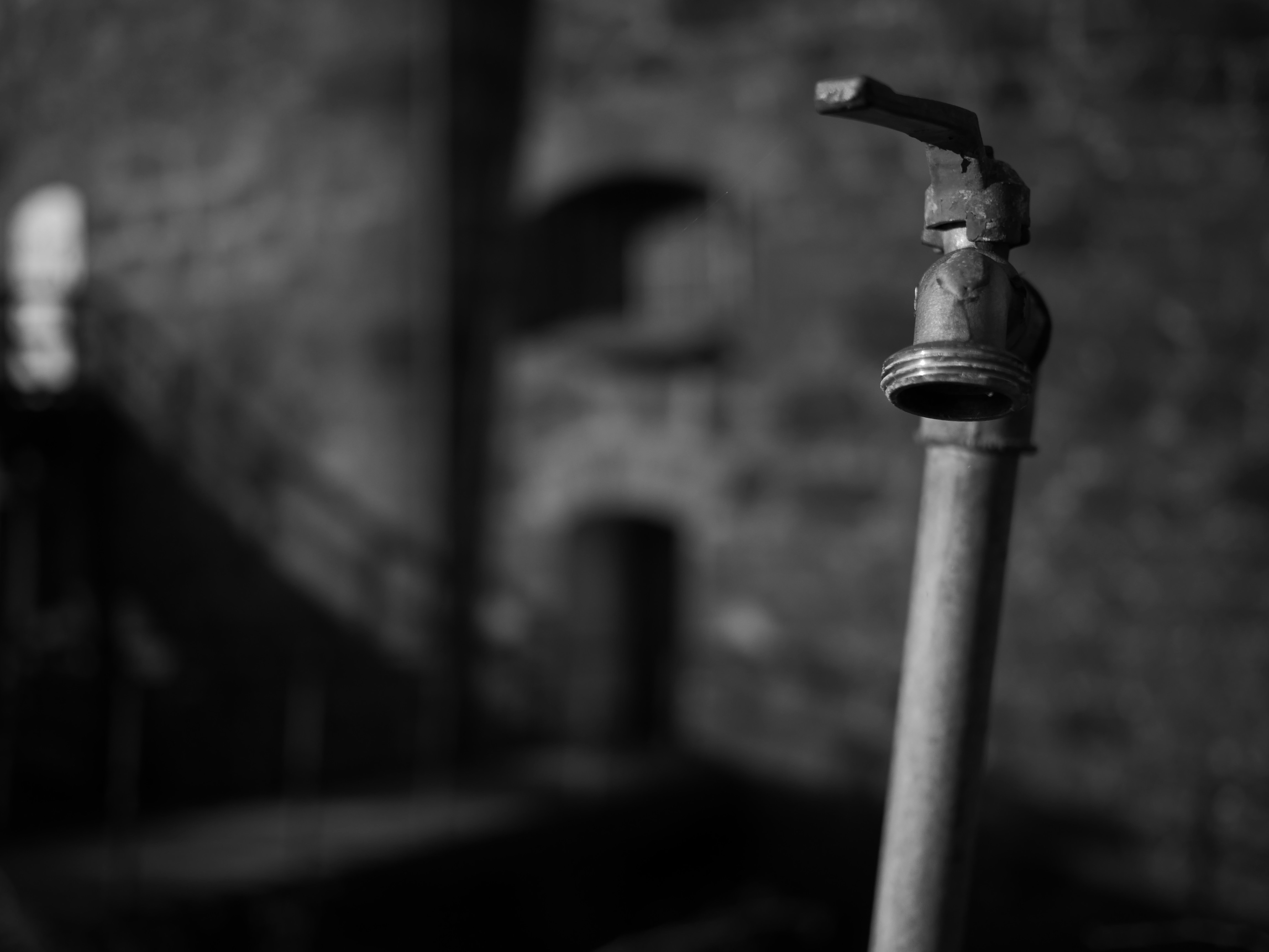 faucet, spigot in front of historical old wall. Black and White. Blurring.