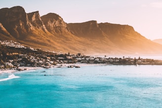 photography of buildings beside seashore and mountain during daytime