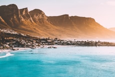 photography of buildings beside seashore and mountain during daytime