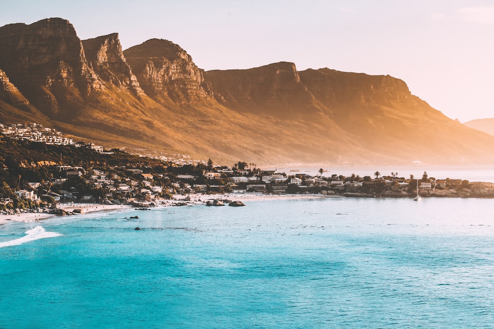 Photographie de bâtiments au bord de la mer et de la montagne pendant la journée