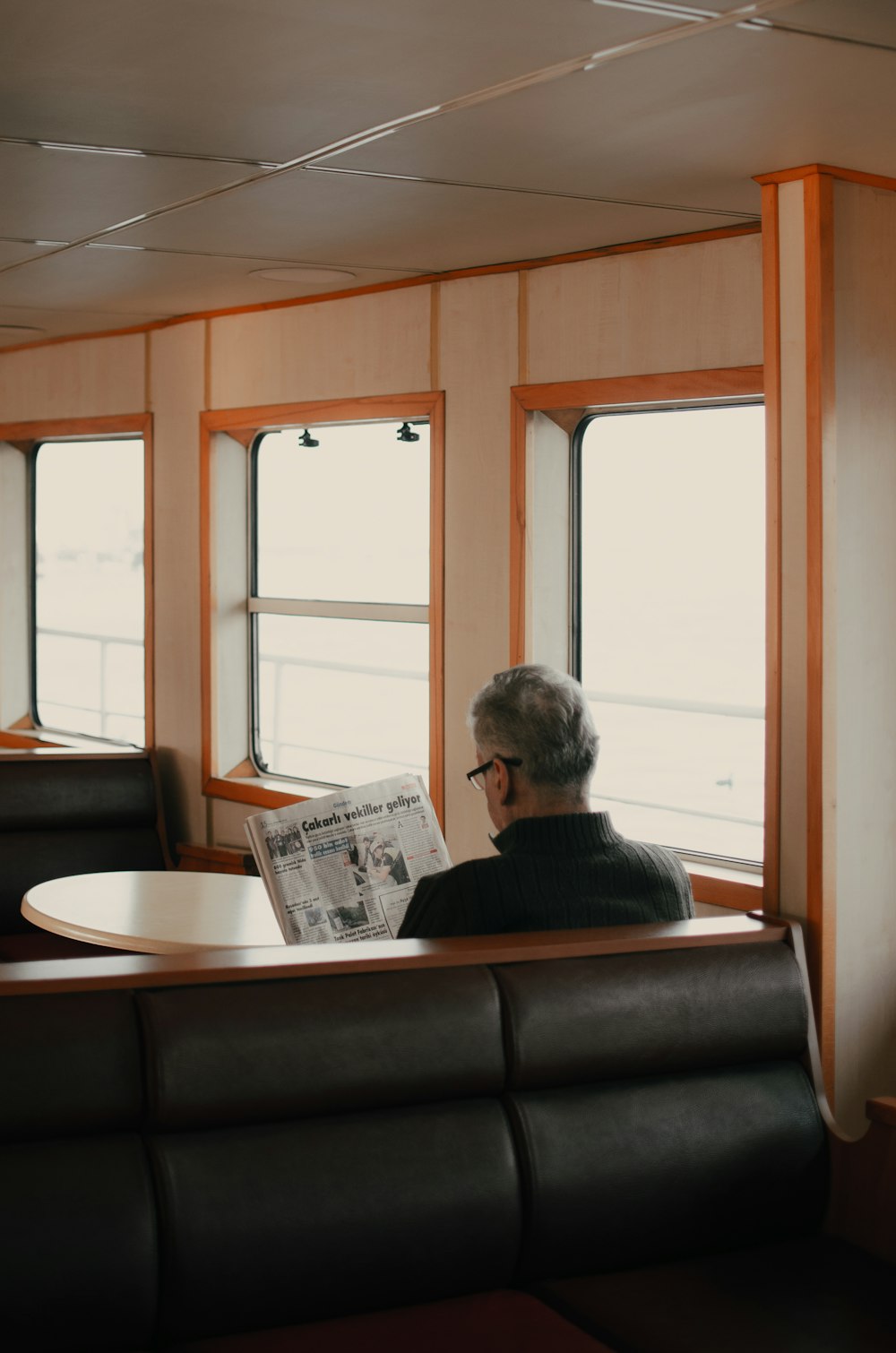 man reads newspaper alone near window inside the train