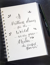Close-up of hands writing goals on a notepad with a motivational quote in the background.