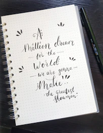 A hand writing in a beautifully designed journal with inspirational quotes.