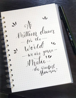 A hand writing in a beautifully designed journal with inspirational quotes.