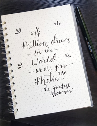An open notebook with a pen, surrounded by motivational quotes.