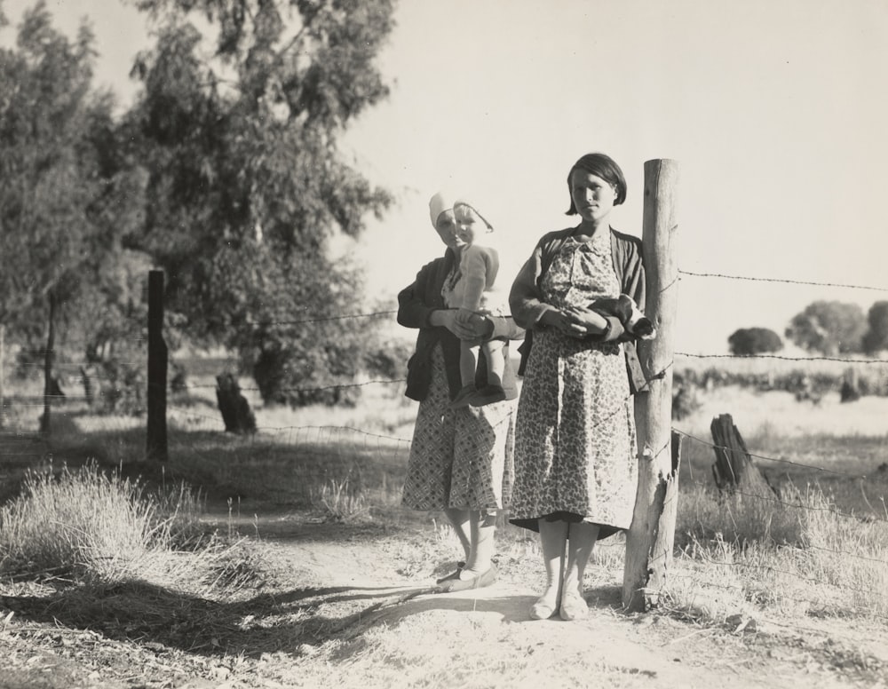 two woman standing and leaning on wood fence with bob wire