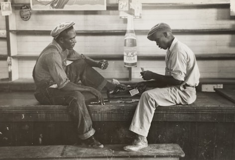 grayscale photo of two men sitting on bench