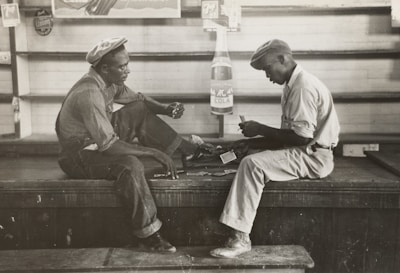grayscale photo of two men sitting on bench